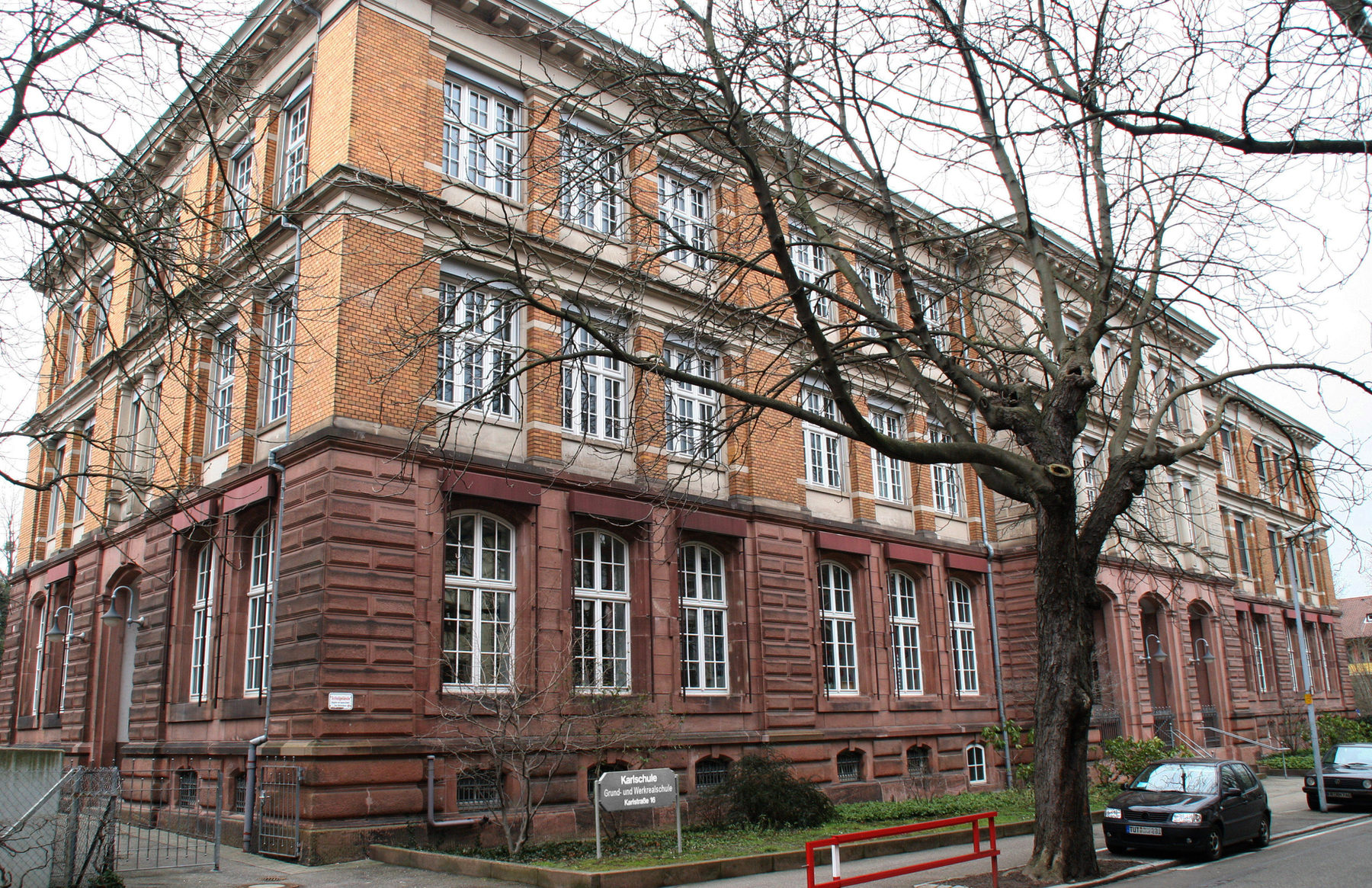 Das Schulhaus der Karlschule: roter Sandstein und gelber Backstein, davor eine große Platane