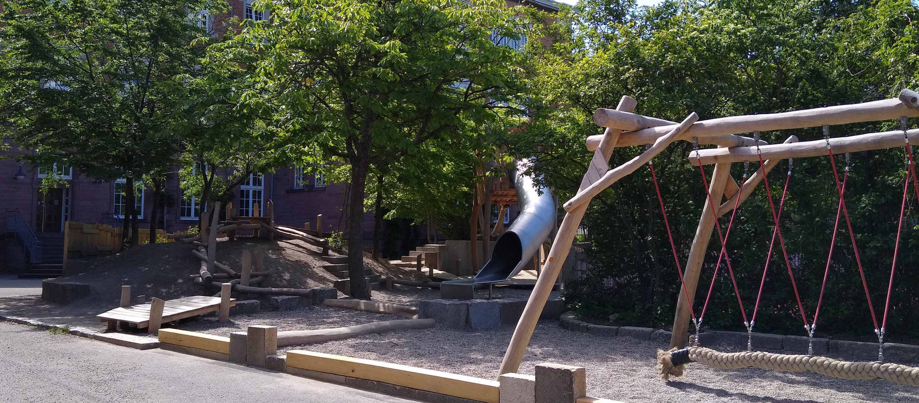Der Schulhof mit Klettergerüst unter alten Bäumen