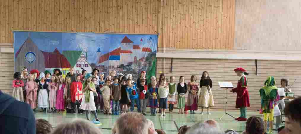 Kinder in Kostümen auf der Bühne der Turnhalle beim Theaterstück Till Eulenspiegel